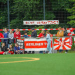 Spielerinnen, Eltern, Freunde und Fans des TSC stehen mit Transparenten an der Seitenlinie.