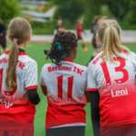 TSC-Mädchen stehen am Spielfeldrand und beobachten die "Großen" beim Warmmachen